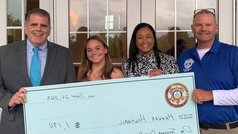 Montgomery County Sheriff's Office Chief Deputy Adam Berry, county Commissioner Jamila Winder, 学生汉娜·豪沙尔, and Sheriff Sean Kilkenny with Hannah's scholarship check